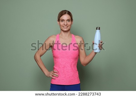 Sportswoman with thermo bottle on green background