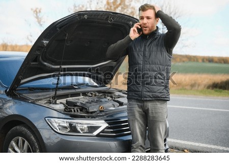 The car broke down, smokes from under the hood, the driver shocked. Royalty-Free Stock Photo #2288283645