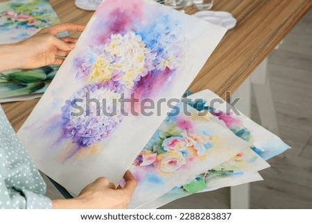 Woman holding painting of flowers indoors, closeup. Watercolor artwork