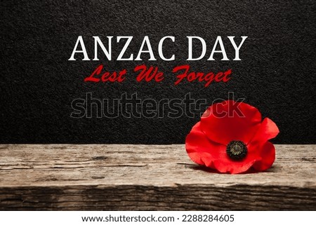 Poppy pin for Anzac Day. Poppy flower on old beautiful high grain, detailed wood on black textured background with text.