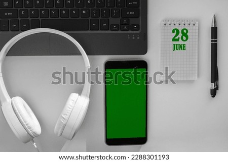 calendar date on a light background of a desktop and a phone with a green screen. June 28 is the twenty-eighth day of the month.