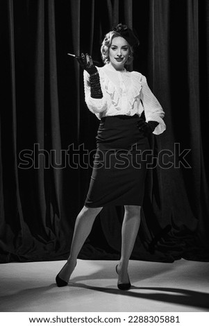 Confident lady. Portrait of charming woman wearing elegant costume smoking and looking at camera. Black and white photo. Concept of beauty, fashion, old films, actress, retro, vintage