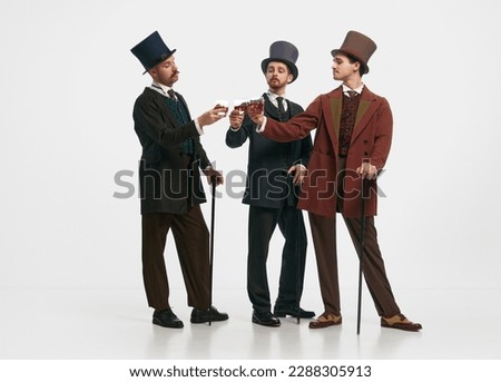Pleasant company of friend and whiskey. Portrait with three men wearing old-fashioned clothes and drinking alcohol over white studio background. Concept of comparison of eras, retro, vintage, retro