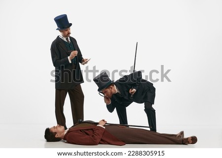 Detectives, murder. Portrait with two men wearing old-fashioned clothes and exposing the crime over white background. Concept of historical remake, comparison of eras, retro, vintage, emotions, mood