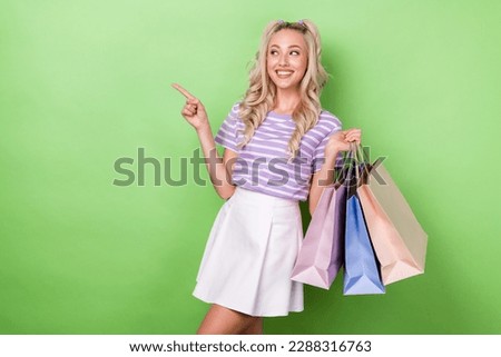Portrait of glamour woman wavy hairstyle tabby t-shirt hold shopping bags look directing empty space isolated on green color background