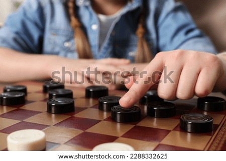 Playing checkers. Mother learning her daughter at table, closeup