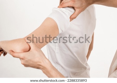 Movement assessment or shoulder joint mobilization. Muscle release. Orthopedic traumatologist examines shoulder joint of patient and checks mobility of movements on white background Royalty-Free Stock Photo #2288335893