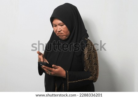 Middle aged Asian women wearing black hijab and abaya, feels sad reacting bad news on mobile phone isolated over white background.