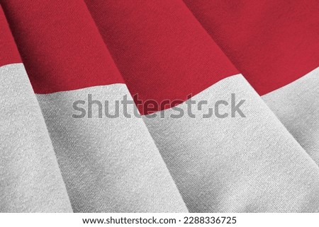 Indonesia flag with big folds waving close up under the studio light indoors. The official symbols and colors in fabric banner
