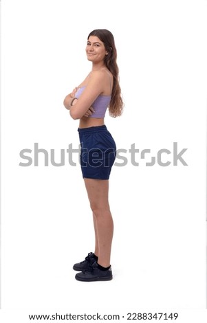 side view of a young girl standing and arms crossed and looking at camera on white background