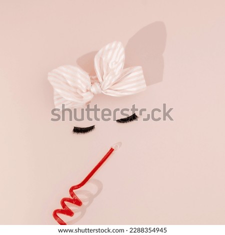Elegant concept made of textile bow, eyelashes and red tube isol