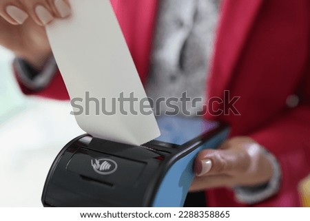 Woman in red jacket holds banking terminal in hand tearing off receipt. Client makes payment for professional lawyer services in office Royalty-Free Stock Photo #2288358865