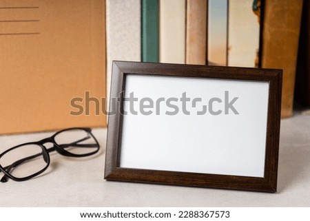 brown empty picture frame and books on the background