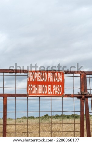 Vertical image of a gate with a sign that prohibits trespassing on private property.