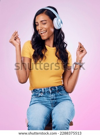 Music, headphones and Indian woman dance on pink background listening to track, audio and radio. Relax, happy and isolated girl singing streaming song for dancing, chilling and happiness in studio
