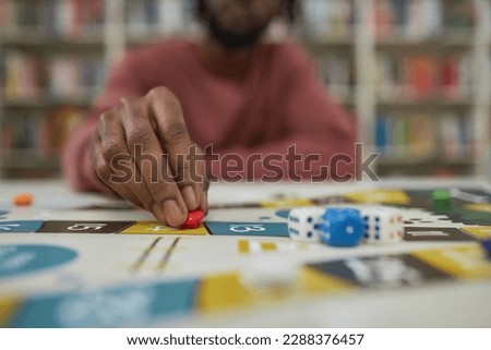 Closeup of black man playing board game with focus on male hand moving game piece, copy space