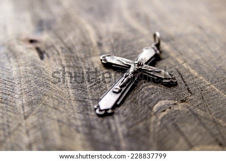 Metal cross lying on the wooden  table, close up