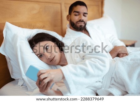 Jealousy Problem. Husband Looking At Cheating Wife When Woman Texting On Smartphone Communicating Online Lying In Bedroom At Home. Jealous Boyfriend Suspecting Affair. Selective Focus Royalty-Free Stock Photo #2288379649