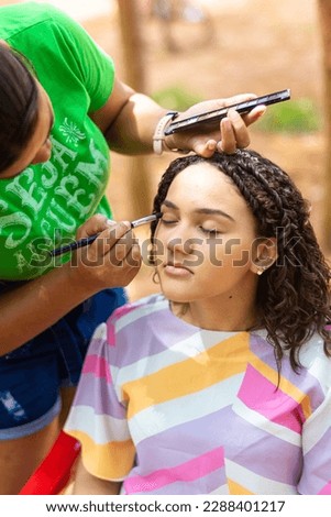 beautiful young woman having her makeup done outdoors for her 15th birthday photo shoot