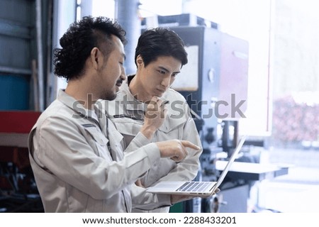 Workers checking processes and safety at a factory or job site while looking at a computer