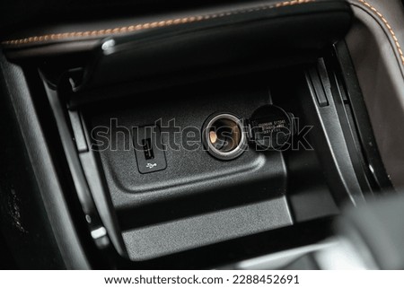 Сlose-up of the car  black interior:  power outlet 12V, USB, AUX and other buttons. 