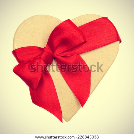 a heart-shaped gift box with a red ribbon on a beige background, with a retro effect