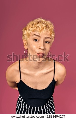 Stock photo of funny girl with her tongue out looking at camera over pink background.