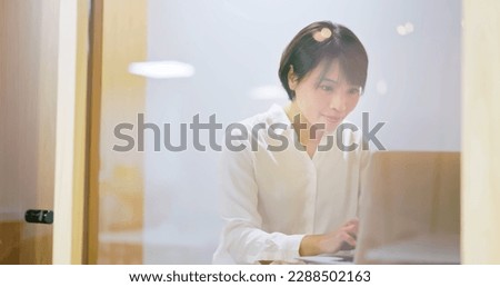 asian cheerful businesswoman sitting on chair is working with laptop computer and mobile phone in personal small office - communicating with customer