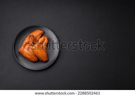 Delicious grilled chicken wings with spices and herbs on a dark concrete background