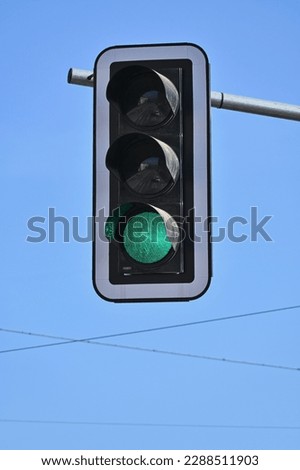 Traffic light with a lit green light on a background of a blue sky