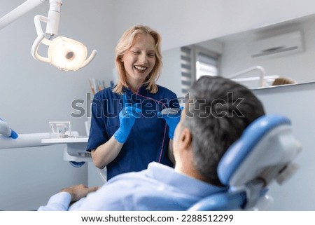 Pretty dentist doctor woman showing jaw model at dental clinic, dental care concept. Dental care concept. Young woman dentist showing male patient jaw model at dental clinic
