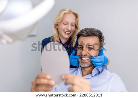 Handsome man smiling while looking at mirror in dental clinic. Shot of a Male patient checking her results in the dentists office