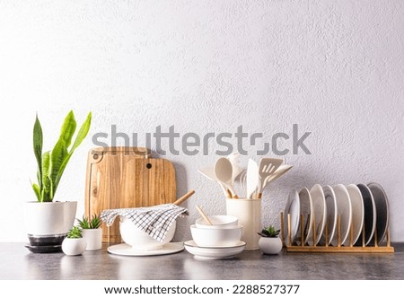 a set of various kitchen utensils and tools, ceramic dishes in light colors on a modern kitchen countertop. front view. a copy space Royalty-Free Stock Photo #2288527377
