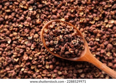 Sichuan pepper and wooden spoons placed throughout the screen. Sichuan pepper is a member of the sansho family used in Chinese cuisine. Viewed from directly above.