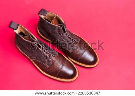 Upper View of Pair of Premium Dark Brown Grain Brogue Derby Boots Made of Calf Leather with Rubber Sole Placed On Pink Background. Horizontal Shot