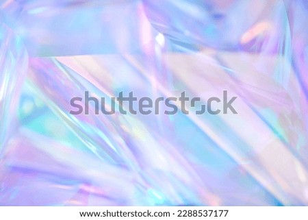 Close-up of ethereal pastel neon blue, purple, lavender, mint holographic metallic foil background. Abstract modern curved blurred surreal futuristic disco, rave, techno, festive dreamlike backdrop Royalty-Free Stock Photo #2288537177
