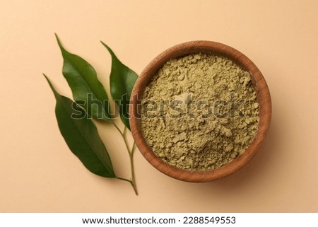 Henna powder and green leaves on beige background, flat lay. Natural hair coloring