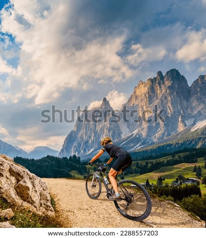Woman ride electric mountain bikes in the Dolomites in Italy. Mountain biking adventure on beautiful mountain trails. Royalty-Free Stock Photo #2288557203