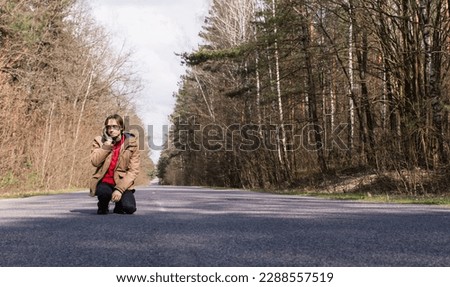 Tinted portrait image of a young guy in a hooded jacket on a forest road outside the city