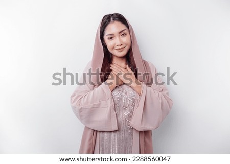 Happy mindful thankful young Asian Muslim woman with her hand on her chest smiling isolated on white background 