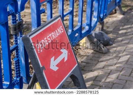 Red rectangular pedestrian sign with blue safety barriers, informational display and travel concept ilustration.