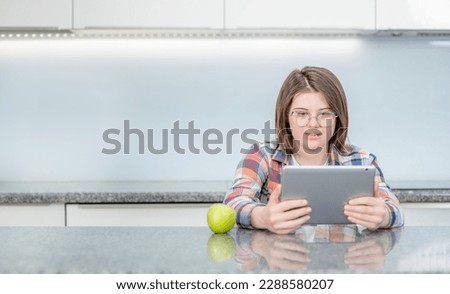 young girl with Downs syndrome using tablet computer at home Royalty-Free Stock Photo #2288580207