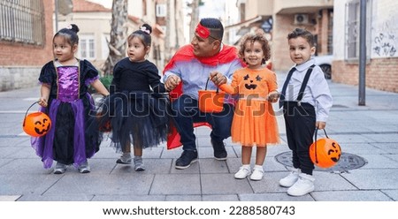Hispanic man and group of kids wearing halloween costume smiling at street