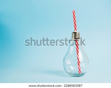 Glass drink bottle with plastic straw on blue background. Concept of earth day, zero waste and plastic recycling