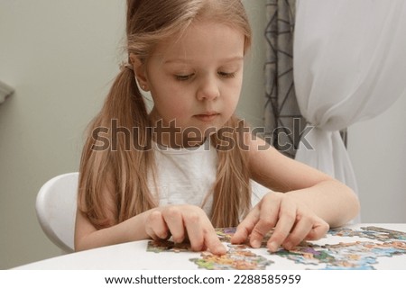 Little child picks up picture from pieces of puzzles, concept of education