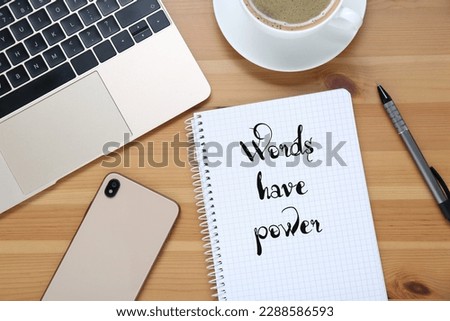 Notebook with phrase Words Have Power, smartphone, laptop, coffee and pen on wooden table, flat lay