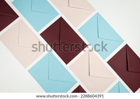 Top view of colourful envelopes on white background. Pink, blue and dark red envelopes flat lay. Post, copy space.