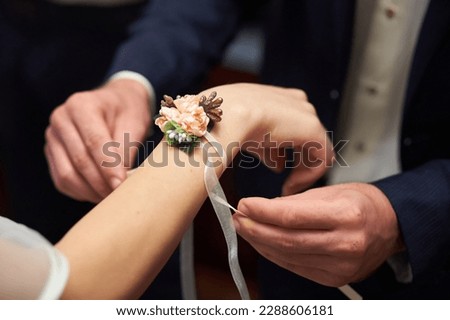 The groom puts a wedding decoration in the form of a flower on the bride's hand Royalty-Free Stock Photo #2288606181
