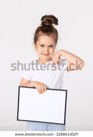 portrait of baby girl holding white drawing Board on white background, young girl is holding a drawing board in her hands. white isolated background