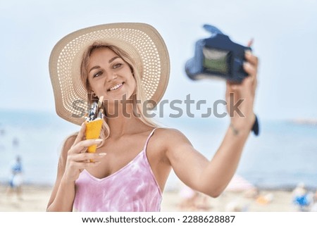 Young blonde woman tourist make selfie by camera eating ice cream at seaside